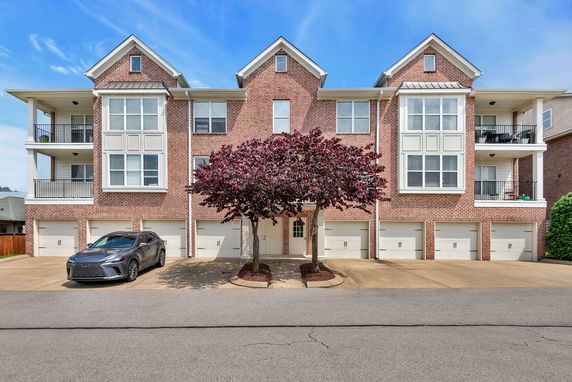 Front view of a three-story brick apartment building with balconies and multiple garages.