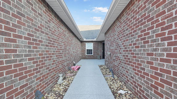 Entrance view of a brick house with a pathway leading to the front door.