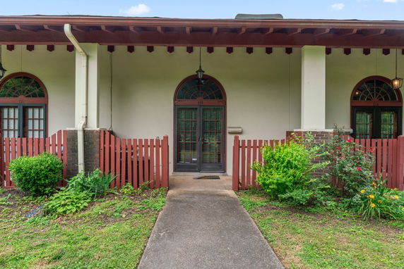 Front view of a single-story house with arched windows and a pathway leading to the door.