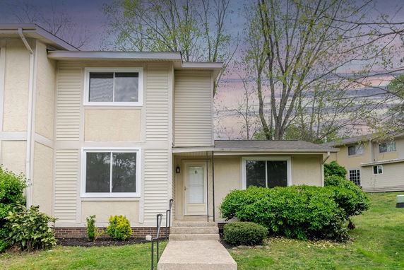 Front view of a two-story house with beige siding and multiple windows.
