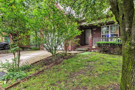 Front view of a brick house with a small porch and front yard.