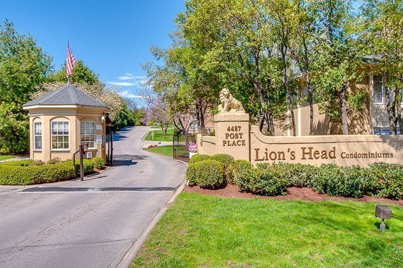 Entrance of a condominium complex with a guardhouse and signage.