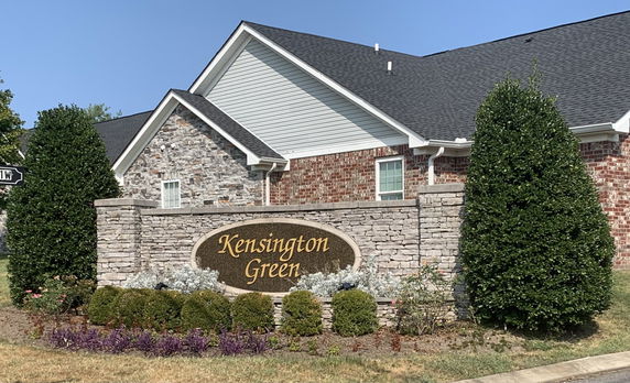 Front view of a building with brick and stone facade and a sign reading Kensington Green.