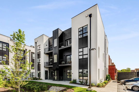 Front view of a modern multi-story apartment building with white and black exteriors.