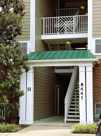 Front view of a building with external stairs and a green roof section.