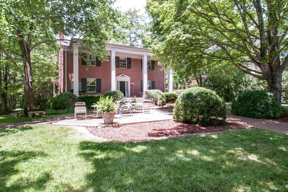 Front view of a two-story brick house with columns and a patio area.