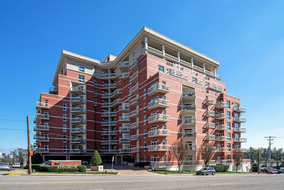 Front view of a multi-story brick apartment building with multiple balconies.