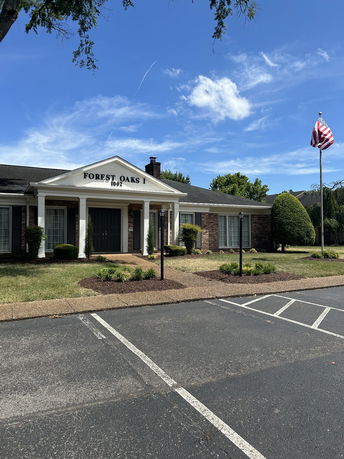 Front view of a single-story building with columns and a flag pole.