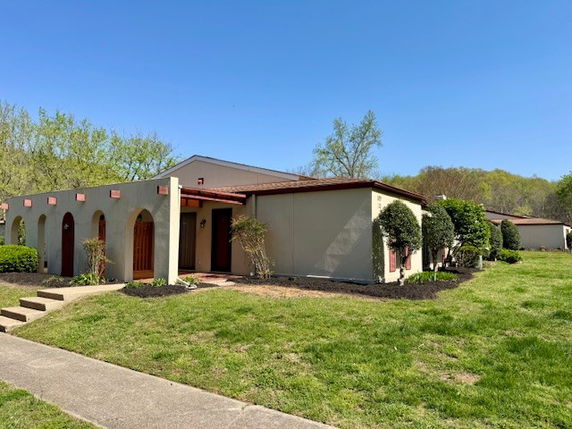 Front view of a single-story house with arched entryways and a flat roof.