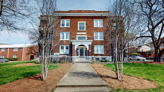 Front view of a brick three-story apartment building with a central entrance.
