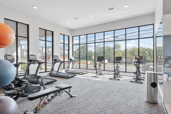 Interior view of a gym with treadmills, stationary bikes, and fitness balls.