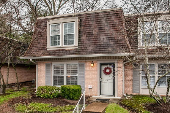 Front view of a two-story townhouse with brown shingle roof and brick exterior.