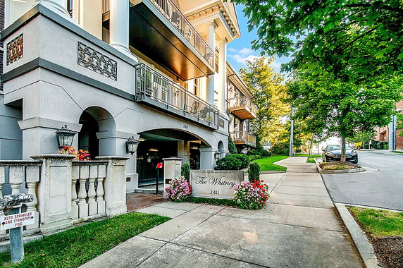 Front view of a multi-story residential building with balconies and decorative columns.