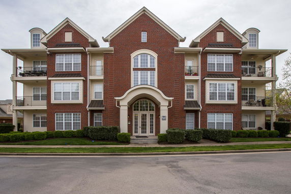 Front view of a multi-story brick apartment building with balconies.