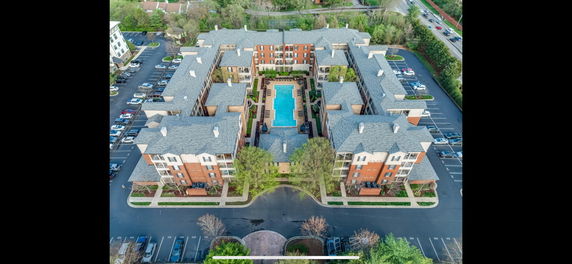 Aerial view of a large residential complex with a central swimming pool and surrounding parking areas.