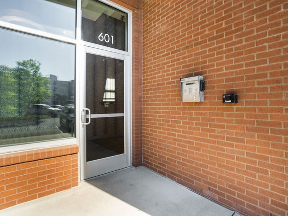 Front view of a building entrance with a glass door and brick wall.