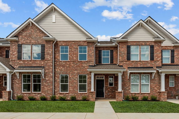 Front view of a two-story brick house with multiple gables and black shutters.