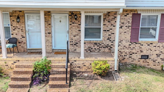 Front view of a brick house with two doors and small steps leading to an entrance.