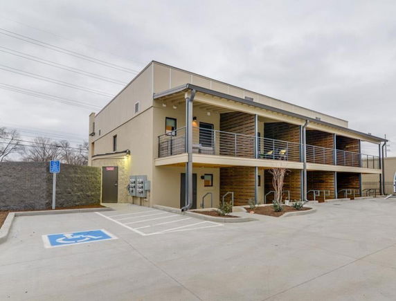 Front view of a two-story building with balconies and parking area.